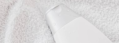 Beyaz havlu arka planında ürün modeli olarak boş etiket kozmetik kutu şişesi