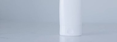 Gri arka planda ürün modeli olarak boş etiket kozmetik kutu şişesi