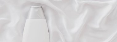 Beyaz ipek arka planda ürün modeli olarak boş etiket kozmetik kutu şişesi