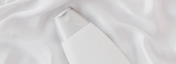 Flacon de récipient cosmétique étiquette vierge comme modèle de produit sur fond de soie blanche — Photo