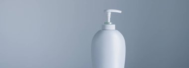 Gri arka planda ürün modeli olarak boş etiket kozmetik kutu şişesi