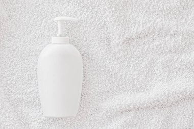 Beyaz havlu arka planında ürün modeli olarak boş etiket kozmetik kutu şişesi