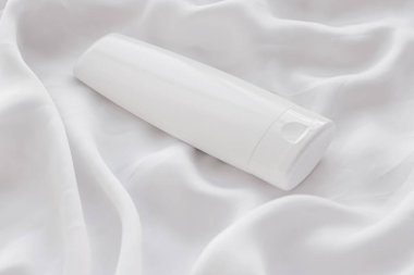 Beyaz ipek arka planda ürün modeli olarak boş etiket kozmetik kutu şişesi