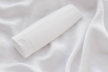 Beyaz ipek arka planda ürün modeli olarak boş etiket kozmetik kutu şişesi