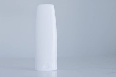 Gri arka planda ürün modeli olarak boş etiket kozmetik kutu şişesi