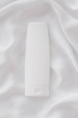 Beyaz ipek arka planda ürün modeli olarak boş etiket kozmetik kutu şişesi