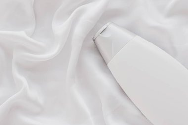 Beyaz ipek arka planda ürün modeli olarak boş etiket kozmetik kutu şişesi