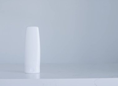 Gri arka planda ürün modeli olarak boş etiket kozmetik kutu şişesi