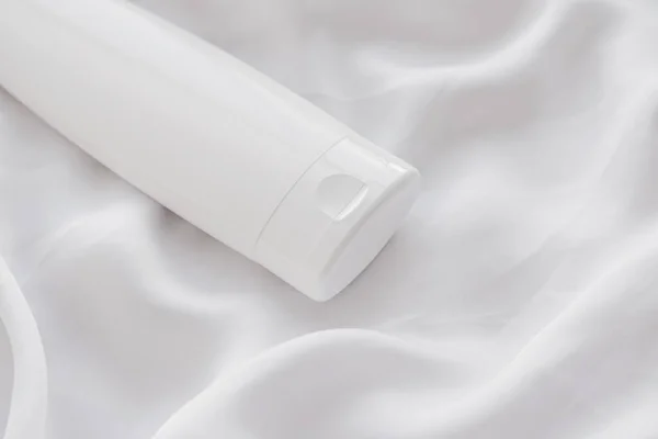 Etiqueta en blanco botella de envase cosmético como maqueta del producto sobre fondo de seda blanca — Foto de Stock