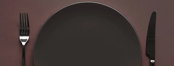 Пустая тарелка и столовые приборы как макет, установленный на темно-коричневом фоне, верхняя посуда для декора стола шеф-повара и брендинг меню — стоковое фото