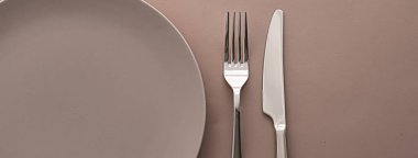 Boş tabak ve çatal bıçak seti kahverengi arka planda, şef masa dekorasyonu ve menü markalaşması için en üst masa takımı