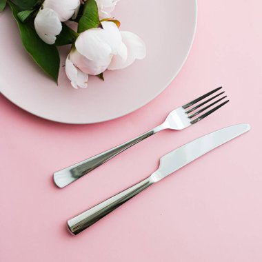Pembe arka planda şakayık çiçekli yemek tabağı ve çatal bıçak seti. Etkinlik dekorasyonu ve menü markalaşması için en üst masa takımı.