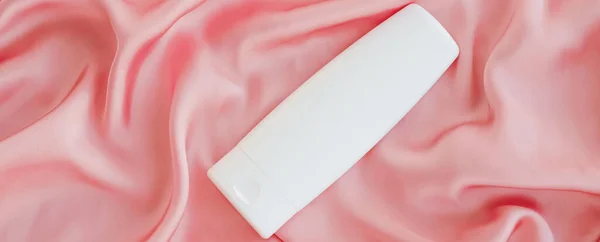 Bottiglia contenitore cosmetico etichetta vuota come modello di prodotto su sfondo di seta rosa — Foto Stock