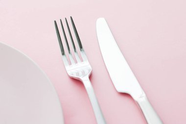Boş tabak ve çatal bıçak seti pembe arka planda, en iyi sofra takımı şef masa dekorasyonu ve menü markalaşması için