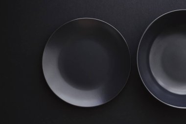 Siyah arka planda boş tabaklar, bayram yemeği için kaliteli bulaşık takımı, minimal tasarım ve diyet