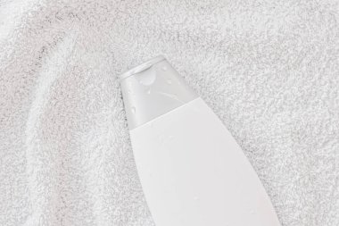 Beyaz havlu arka planında ürün modeli olarak boş etiket kozmetik kutu şişesi