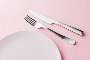 Boş tabak ve çatal bıçak seti pembe arka planda, en iyi sofra takımı şef masa dekorasyonu ve menü markalaşması için