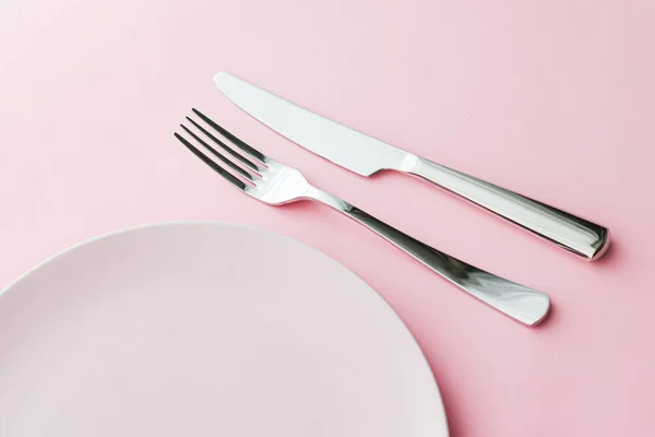 Placa vacía y cubiertos como juego de maquetas sobre fondo rosa, vajilla superior para la decoración de la mesa del chef y la marca del menú —  Fotos de Stock
