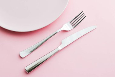 Boş tabak ve çatal bıçak seti pembe arka planda, en iyi sofra takımı şef masa dekorasyonu ve menü markalaşması için