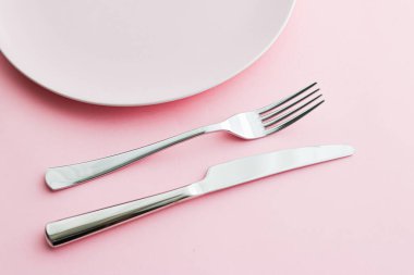 Boş tabak ve çatal bıçak seti pembe arka planda, en iyi sofra takımı şef masa dekorasyonu ve menü markalaşması için
