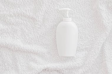 Beyaz havlu arka planında ürün modeli olarak boş etiket kozmetik kutu şişesi