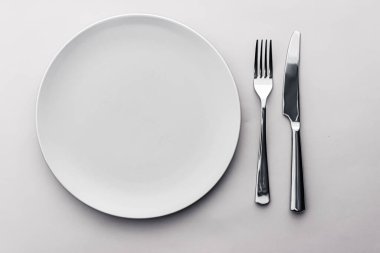 Boş tabak ve çatal bıçak seti beyaz arka planda, şef masa dekorasyonu ve menü markalaşması için en üst masa takımı