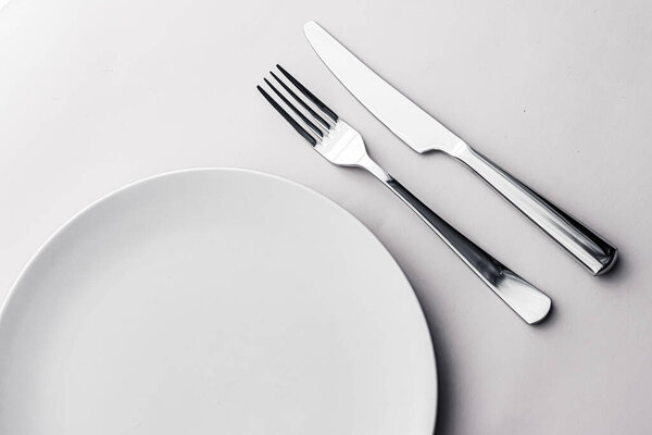 Empty plate and cutlery as mockup set on white background, top tableware for chef table decor and menu branding