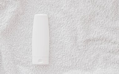 Beyaz havlu arka planında ürün modeli olarak boş etiket kozmetik kutu şişesi