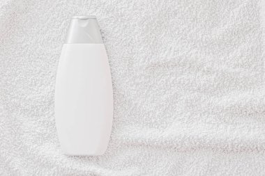 Beyaz havlu arka planında ürün modeli olarak boş etiket kozmetik kutu şişesi