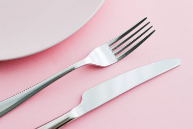 Boş tabak ve çatal bıçak seti pembe arka planda, en iyi sofra takımı şef masa dekorasyonu ve menü markalaşması için