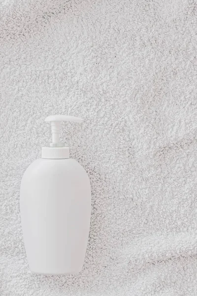 Blank label cosmetic container bottle as product mockup on white towel background — Stock Photo, Image