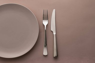 Boş tabak ve çatal bıçak seti kahverengi arka planda, şef masa dekorasyonu ve menü markalaşması için en üst masa takımı