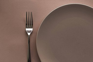 Boş tabak ve çatal bıçak seti kahverengi arka planda, şef masa dekorasyonu ve menü markalaşması için en üst masa takımı
