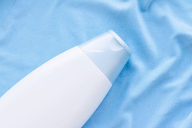 Mavi ipek arka planda boş etiket şampuan şişesi veya duş jeli modeli, güzellik ürünü ve vücut bakımı kozmetiği