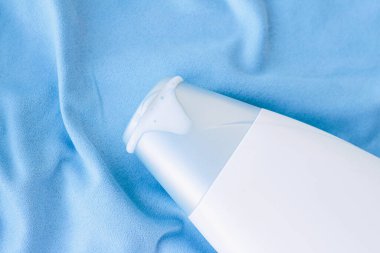 Mavi ipek arka planda boş etiket şampuan şişesi veya duş jeli modeli, güzellik ürünü ve vücut bakımı kozmetiği