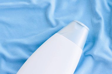 Mavi ipek arka planda boş etiket şampuan şişesi veya duş jeli modeli, güzellik ürünü ve vücut bakımı kozmetiği