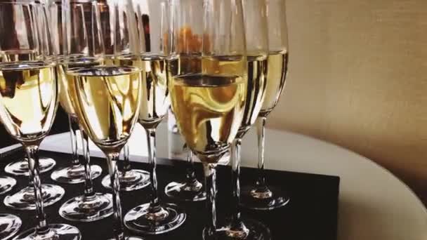 Ποτήρια σαμπάνιας και λευκού αφρώδους οίνου σε χρυσό φως διακοπών σε εορταστική εκδήλωση, πολυτελή γάμο και εγκαίνια — Αρχείο Βίντεο