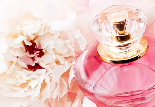 Şakayık çiçeklerinin, parfüm reklamlarının ve güzellik markalarının arka planında şık bir parfüm ürünü olarak lüks bir parfüm şişesi. — Stok fotoğraf