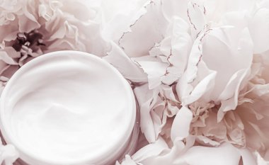 Lüks kozmetik krem kavanozu. Şakayık çiçeklerinin, vücut nemlendiricisinin ve güzellik markalarının arka planında yaşlanma karşıtı rutin bir ürün.