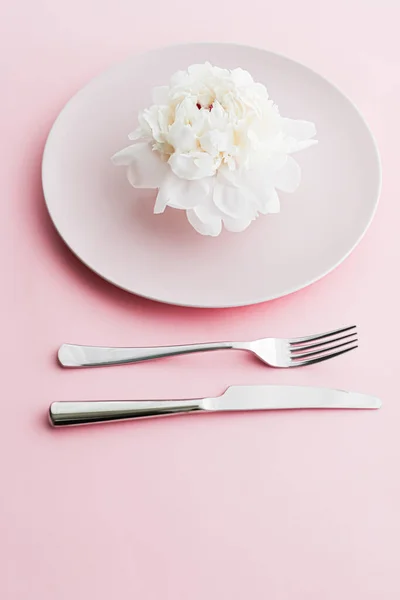 Placa de comedor y cubiertos con flor de peonía como decoración de la boda sobre fondo rosa, vajilla superior para la decoración del evento y menú de postres —  Fotos de Stock