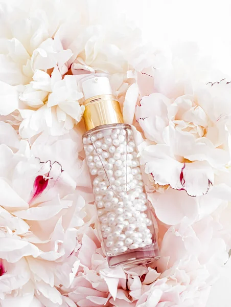 Luxurious cosmetic bottle as antiaging skincare product on background of flowers, blank label packaging for body care branding