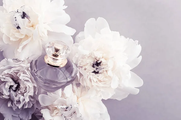 Flacon de parfum violet comme produit de parfum de luxe sur fond de fleurs de pivoine, annonce de parfum et marque de beauté — Photo