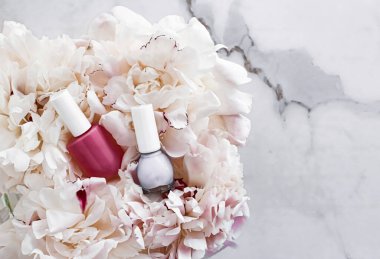 Çiçek arka planında tırnak cilası şişeleri, Fransız manikürü ve kozmetik marka.