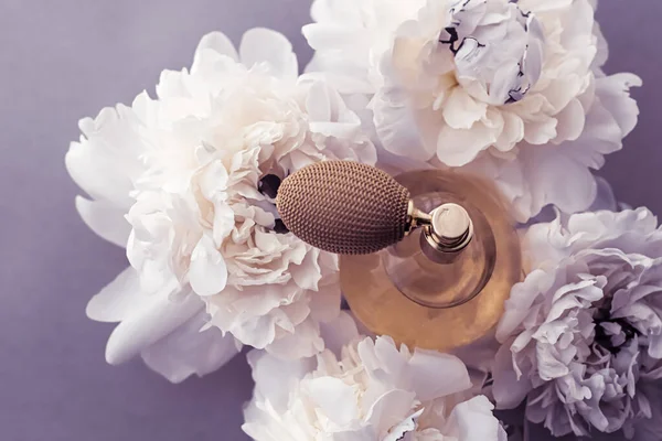 Luxe fragrance bottle as vintage perfume product on violet background and peony flowers, parfum ad and beauty branding