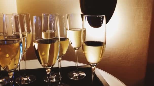 Ποτήρια σαμπάνιας και λευκού αφρώδους οίνου σε χρυσό φως διακοπών σε εορταστική εκδήλωση, πολυτελή γάμο και εγκαίνια — Αρχείο Βίντεο
