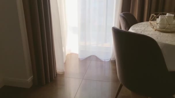 Vista de uma sala de jantar, mesa redonda, cadeiras e janela decorada com cortinas, móveis e design de interiores de luxo — Vídeo de Stock