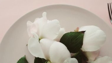 Tabağında şakayık çiçekleri olan bej masa seti ve lüks yemek, düğün ya da doğum günü kutlaması için çatal bıçak takımı.