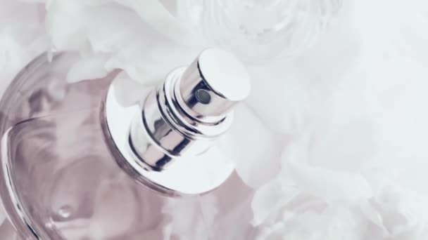 Frasco de perfume blanco con flores de peonía, aroma de fragancia elegante como cosmético de lujo, fondo de productos de moda y belleza — Vídeo de stock