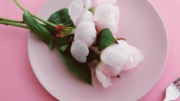 Růžový stůl s pivoňkovými květy na talíři a příbory pro luxusní večeři, svatbu nebo oslavu narozenin — Stock video
