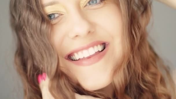 Щаслива жінка посміхається і сміється, довге коричневе хвилясте волосся, природний макіяж і здорові білі зуби, обличчя і краса — стокове відео
